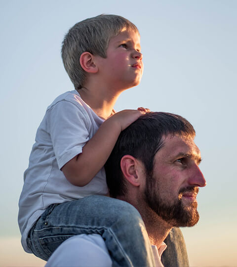 Small Child Sits on the Shoulders of His Grandfather